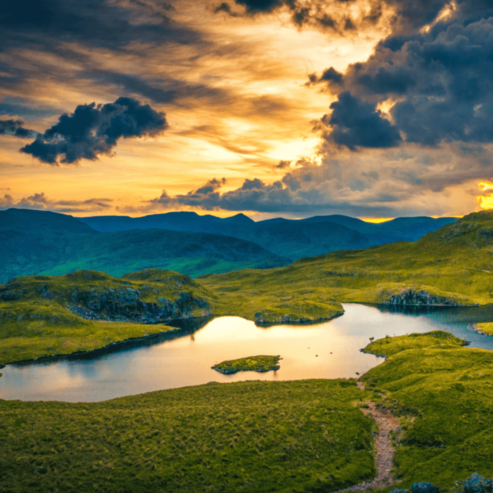 A breathtaking landscape of a serene lake surrounded by lush green hills at sunset. Golden hues illuminate the sky, casting reflections on the water. Dramatic clouds add depth to the scene, creating a tranquil and picturesque view.
