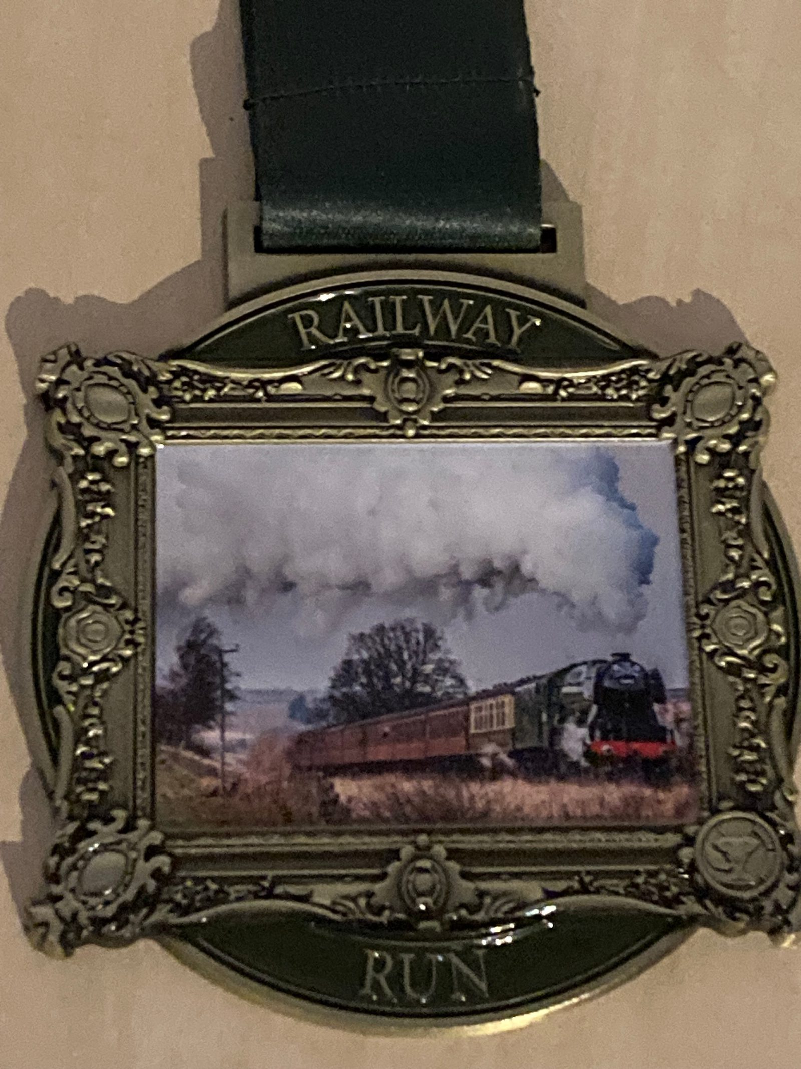 A decorative medal with a vintage-style frame shows a steam train moving through the countryside, with white smoke billowing above. The medal reads "RAILWAY RUN" at the top and bottom.