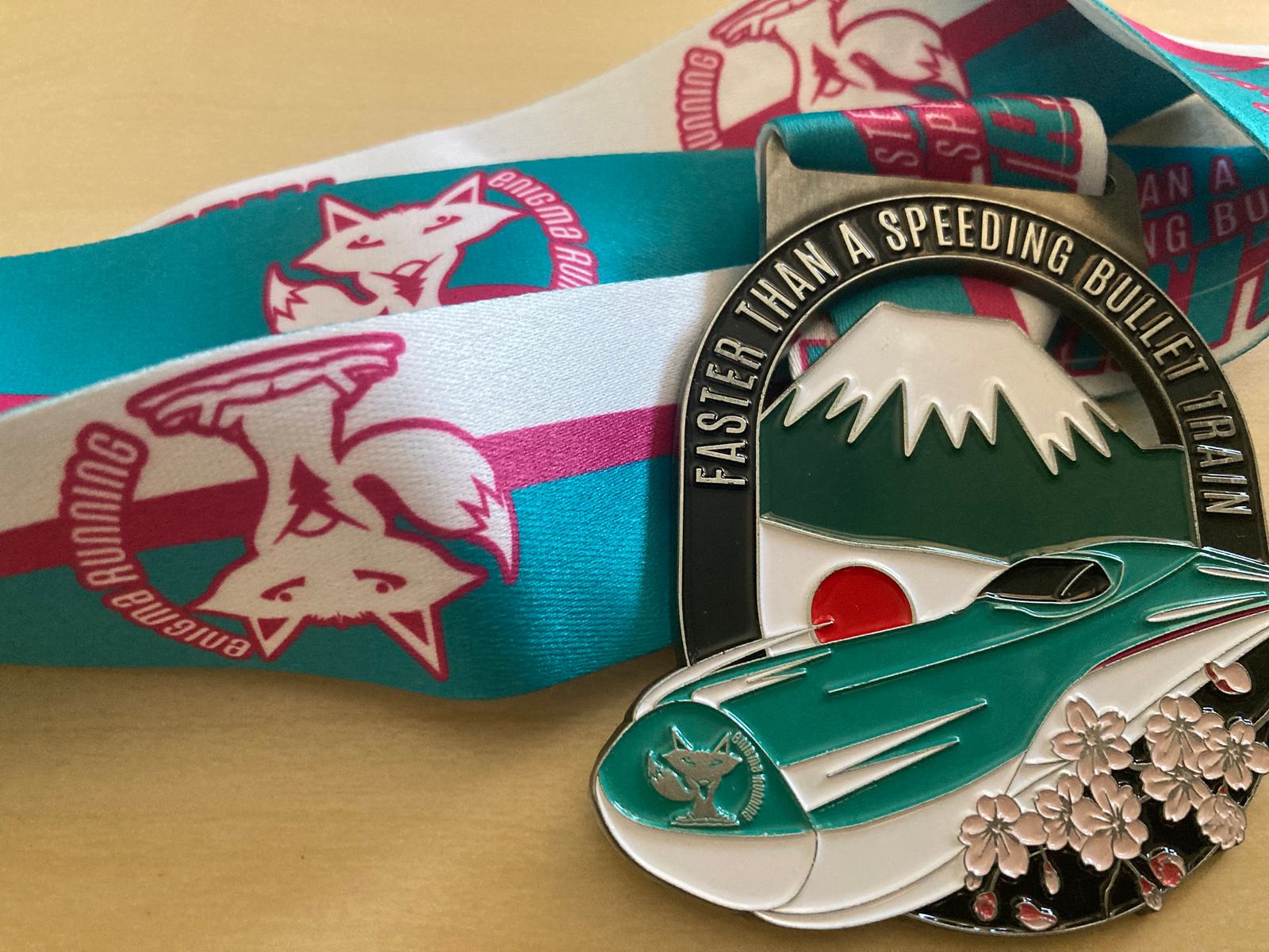 A medal with a ribbon. The medal features a depiction of a bullet train in front of a mountain, with cherry blossoms and the flag of Japan, along with text that reads "Faster than a speeding bullet train." The ribbon shows a fox logo with the text "Awesome Running.