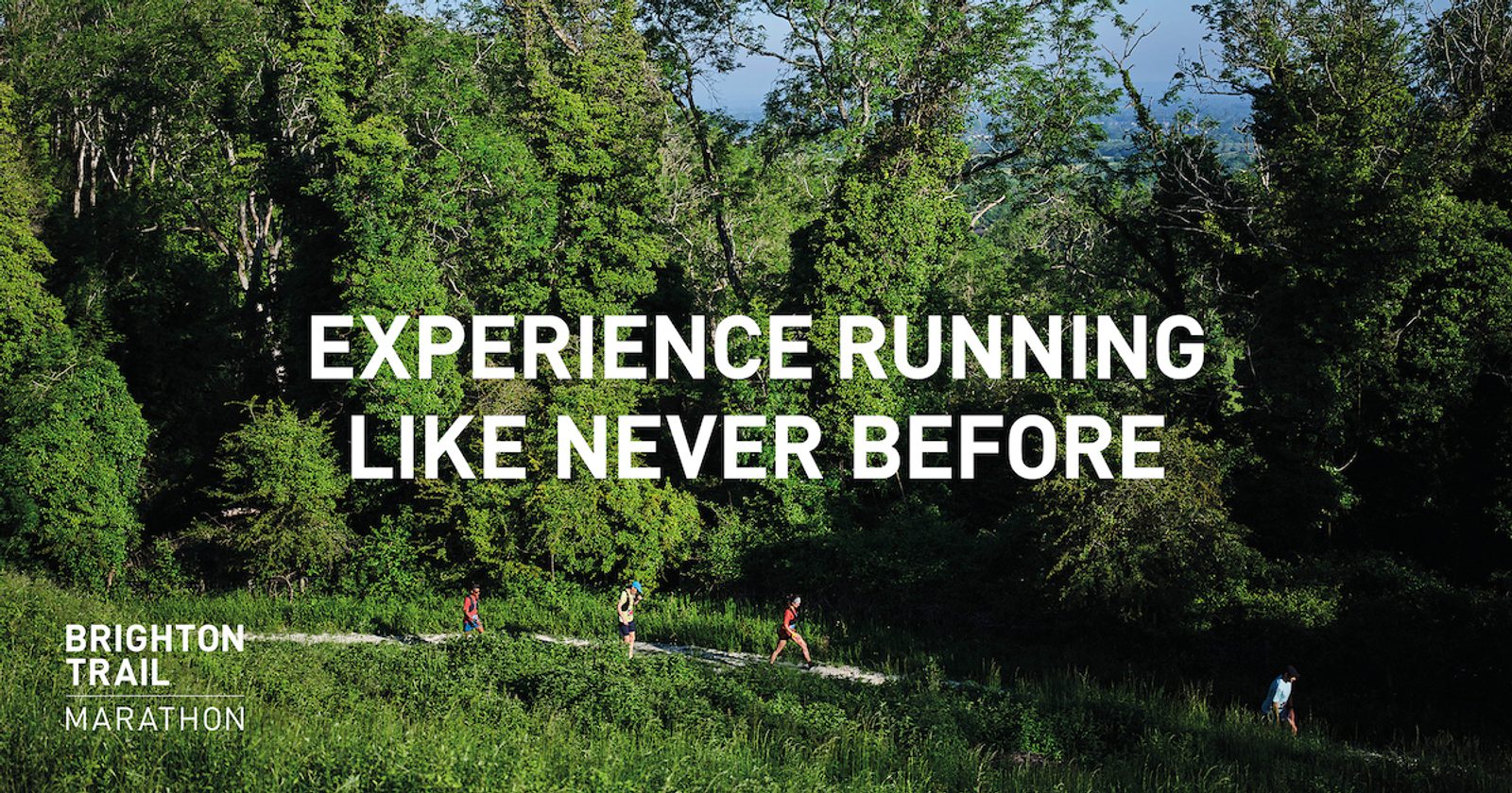 An image of a lush green forest with trees and dense foliage. Several runners can be seen on a trail cutting through the forest. The text overlay reads, "Experience running like never before." In the bottom left corner, the text reads, "Brighton Trail Marathon.