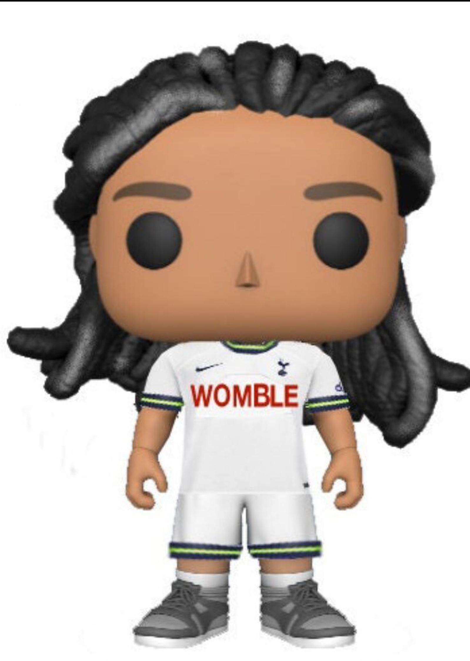 A Funko Pop figure with long, dark braided hair is dressed in a white soccer uniform, featuring the name "WOMBLE" and a team logo on the front. The figure is wearing gray and white sneakers.