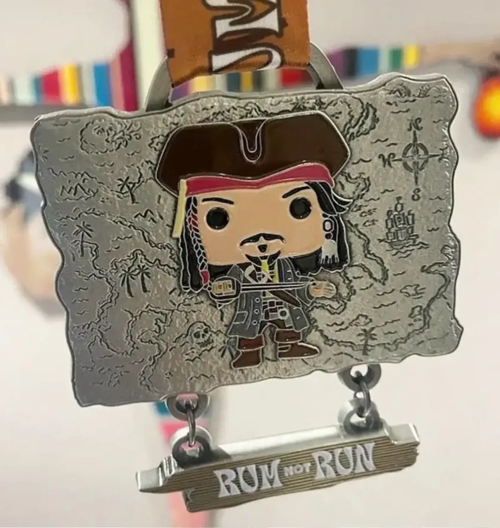 A decorative medal features a chibi-style pirate character in a hat, holding a sword, set against a map background. Below, a hanging plaque reads "RUN NOT RUM" in bold letters. The medal is attached to a colorful ribbon.