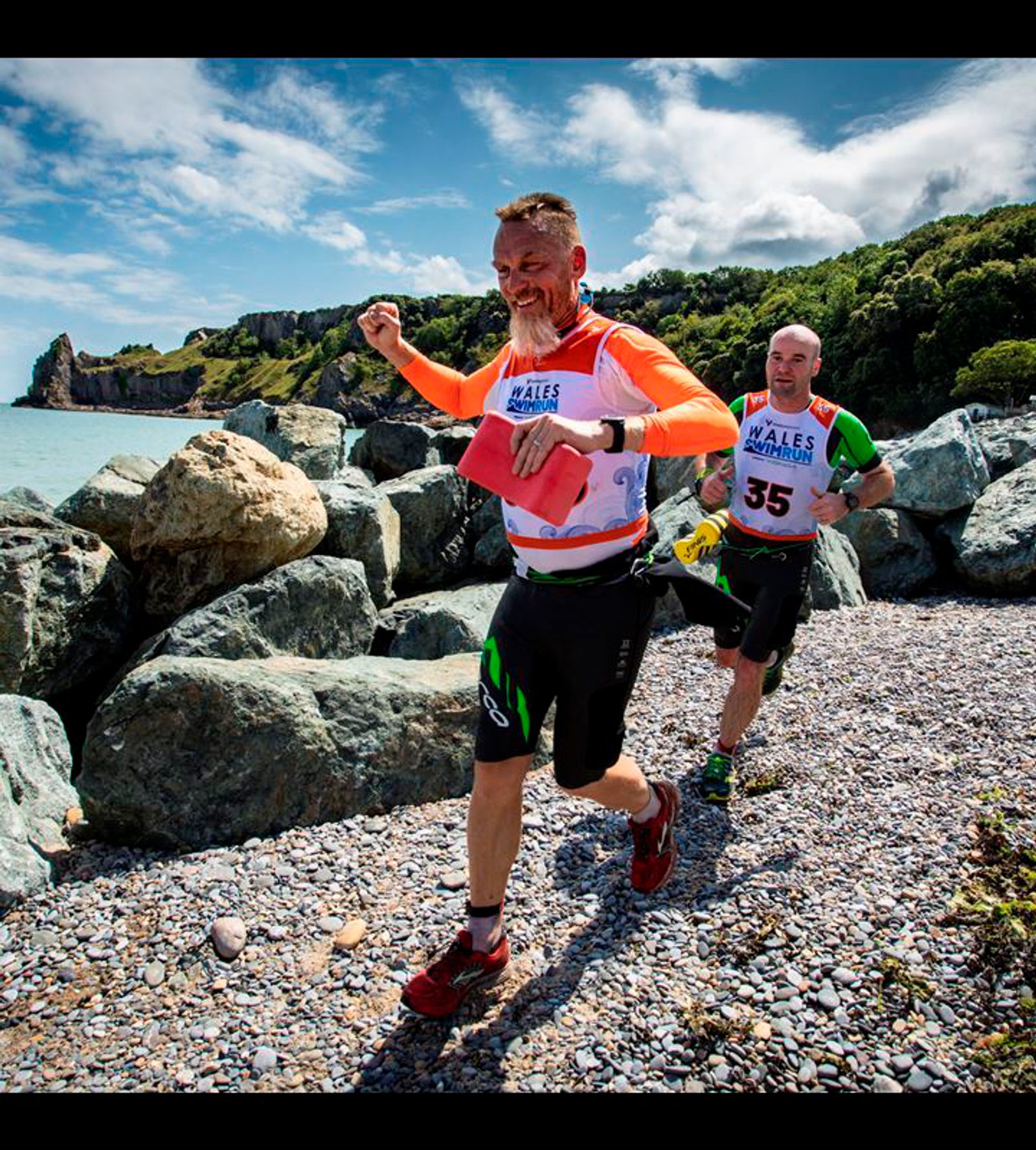 A group of men running on a rocky beach.