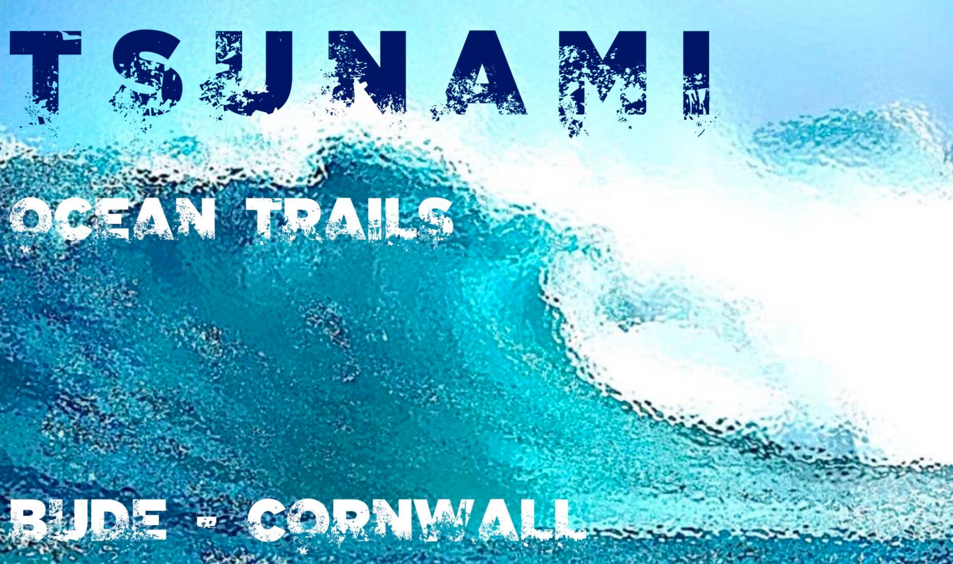 Poster featuring a massive ocean wave with the text "TSUNAMI" at the top. Below, it reads "OCEAN TRAILS" in a smaller font, and at the bottom, it says "BUDE - CORNWALL". The text is designed to blend with the wave graphic.