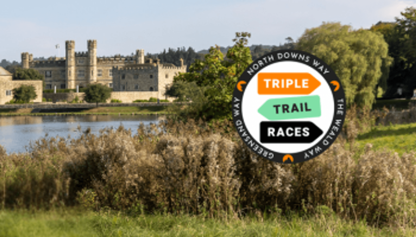 A historic castle stands by a tranquil lake surrounded by greenery. In the foreground is a circular logo with the words "North Downs Way," "Greensand Way," "Weald Way," and "Triple Trail Races.