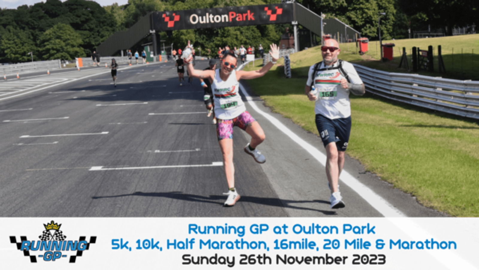 A group of runners are on a sunny track at Oulton Park. In the foreground, a woman in colorful running gear leaps joyfully with arms raised, while a man in a white shirt runs beside her, smiling and waving. The event banner reads: "Running GP at Oulton Park, Sunday 26th November 2023.