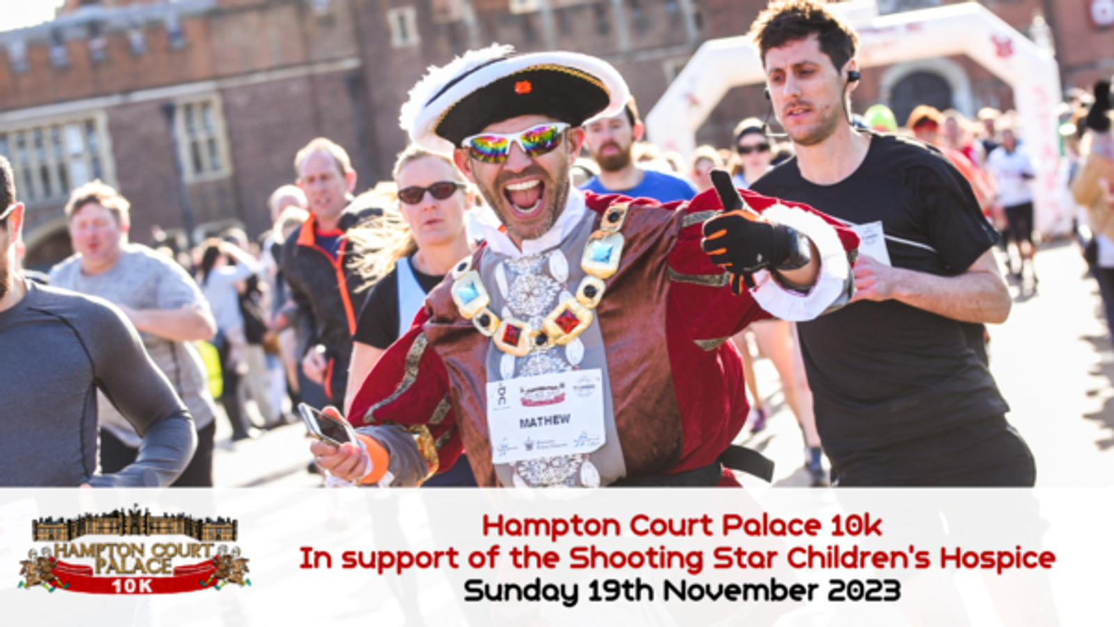 A man in a vibrant, historical costume runs a race, smiling and holding an object in one hand. He's wearing a large hat, sunglasses, and a bib labeled "Matthew." Other runners and a building are visible in the background. Text reads "Hampton Court Palace 10k" and event details.