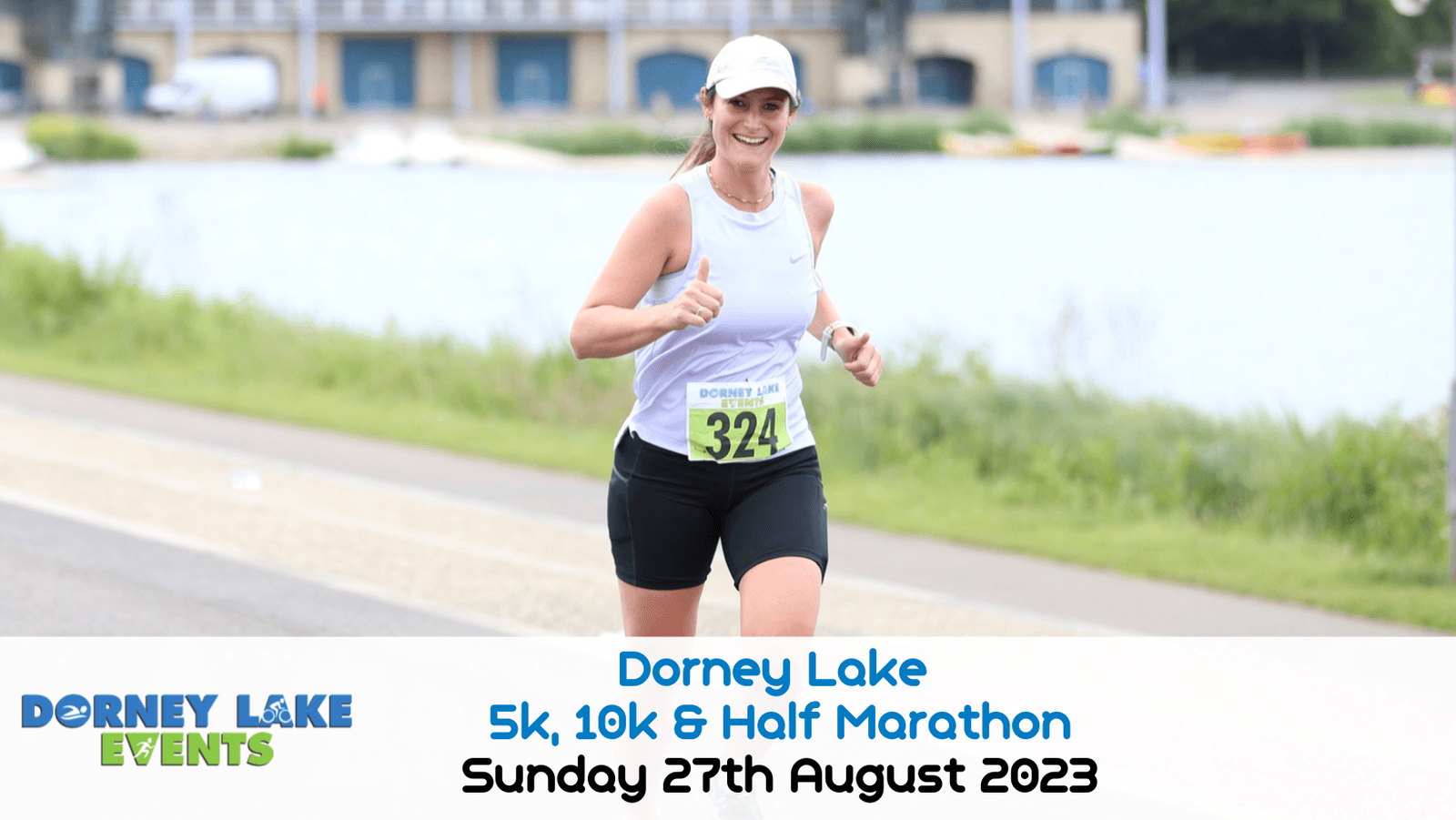A runner wearing a white tank top and black shorts smiles while running along a waterside path. She is participating in the Dorney Lake 5k, 10k & Half Marathon event. The date "Sunday 27th August 2023" is displayed at the bottom. Her race number is 324.