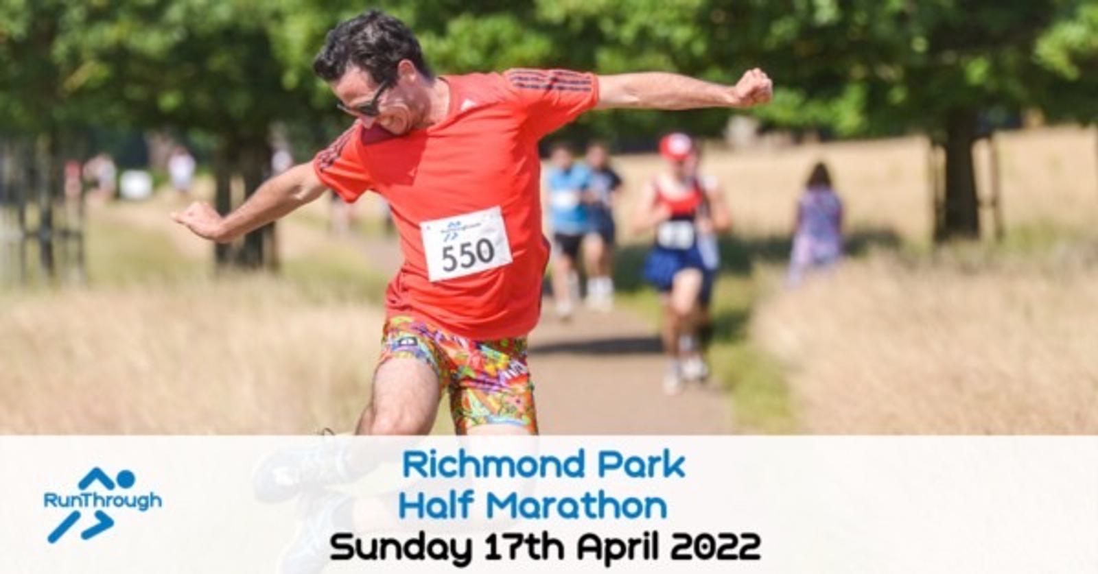 A runner in a bright red shirt and colorful shorts is energetically running on a trail during the Richmond Park Half Marathon on Sunday, April 17th, 2022. He's wearing bib number 550. Other runners can be seen in the background.