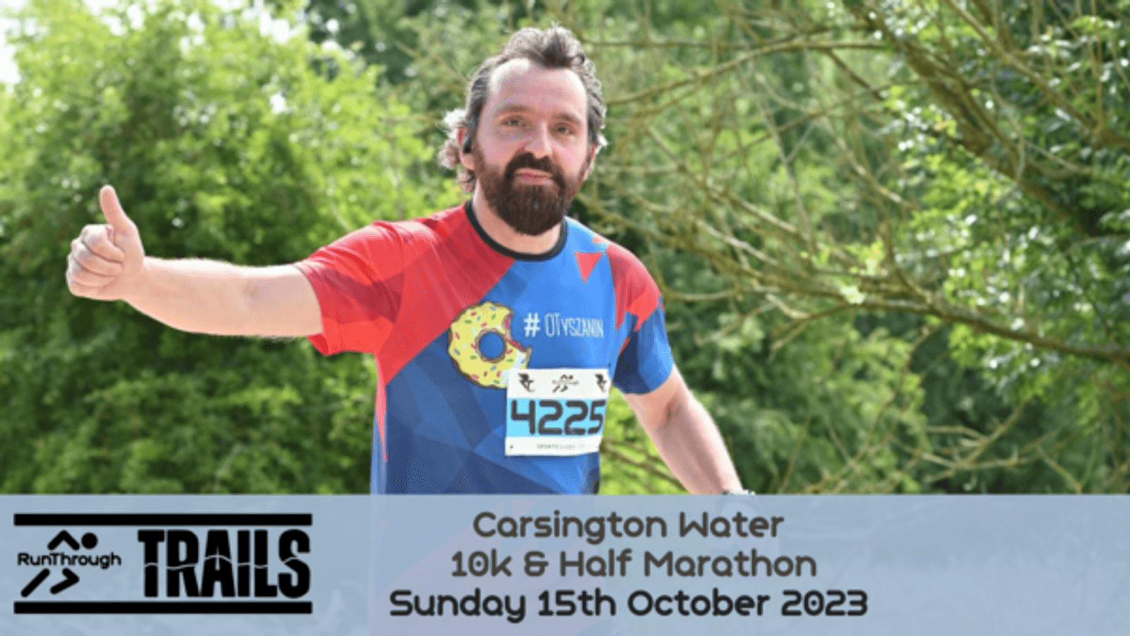 A man with a beard, wearing a red and blue running shirt with the number 4225, gives a thumbs up while running. The event is the Carsington Water 10k & Half Marathon, taking place on Sunday 15th October 2023. The background features greenery and trees.