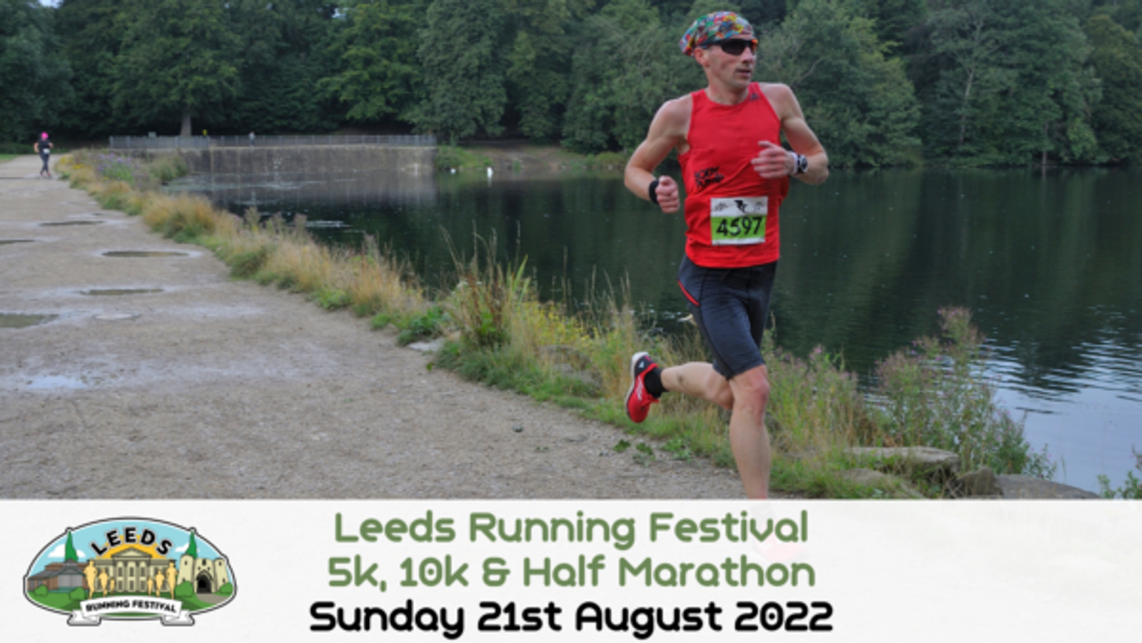 A runner in a red shirt and black shorts is mid-stride on a path beside a body of water during the Leeds Running Festival. He is wearing sunglasses and a headband, with bib number 479. The event's banner at the bottom reads "Leeds Running Festival 5k, 10k & Half Marathon, Sunday 21st August 2022.