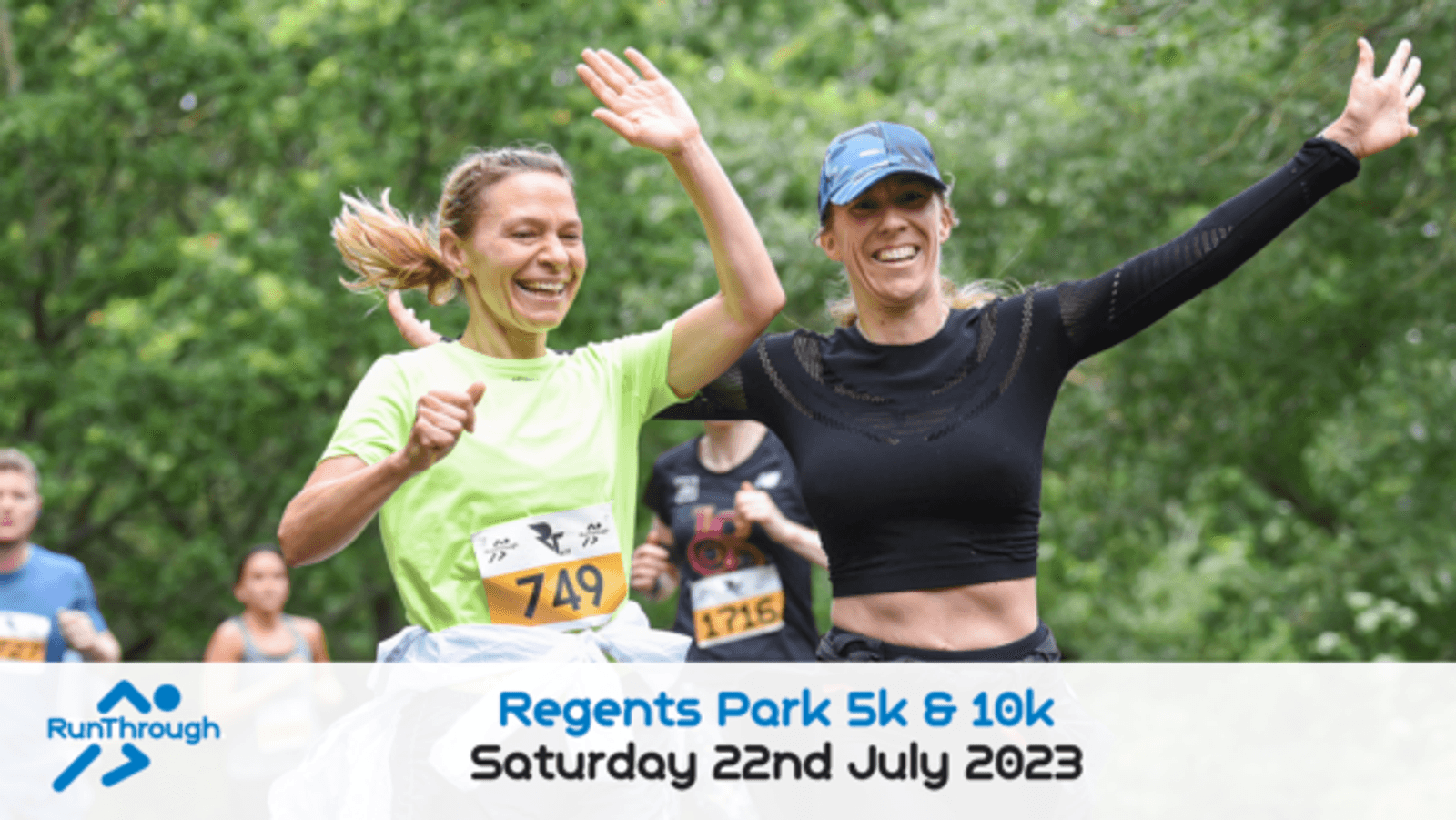 Two women, one in a green shirt and the other in black, joyfully run with their arms raised in Regents Park during a 5k and 10k event on July 22nd, 2023. Other runners are visible in the blurred background.