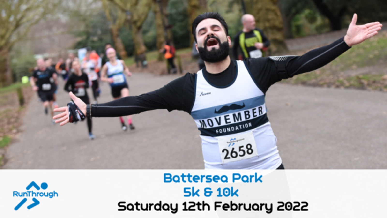 A runner with a beard and mustache enthusiastically spreads his arms wide as he nears the finish line in a park. He wears a bib numbered 2658 and a vest with "Movember Foundation" on it. Other participants can be seen running behind him. Text reads: "Battersea Park 5k & 10k, Saturday 12th February 2022.