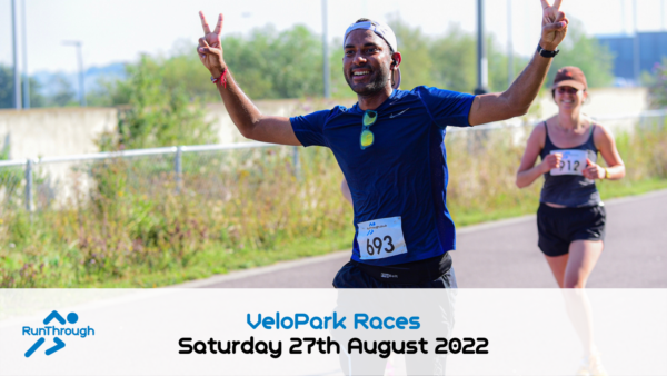 A man and a woman are running on a path with greenery in the background. The man in front is wearing a blue shirt, showing two peace signs, and has a race bib numbered 693. The woman behind wears a visor and a race bib numbered 312. Text reads: "VeloPark Races, Saturday 27th August 2022.