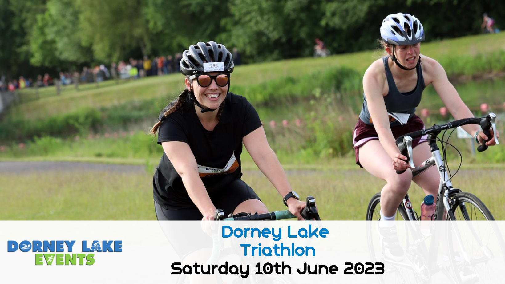 Two cyclists, one wearing black and the other in a white tank top, participate in the Dorney Lake Triathlon on June 10th, 2023. Both are smiling and wearing helmets and sunglasses, with grassy scenery and more participants in the background. "Dorney Lake Events" text overlays the image.