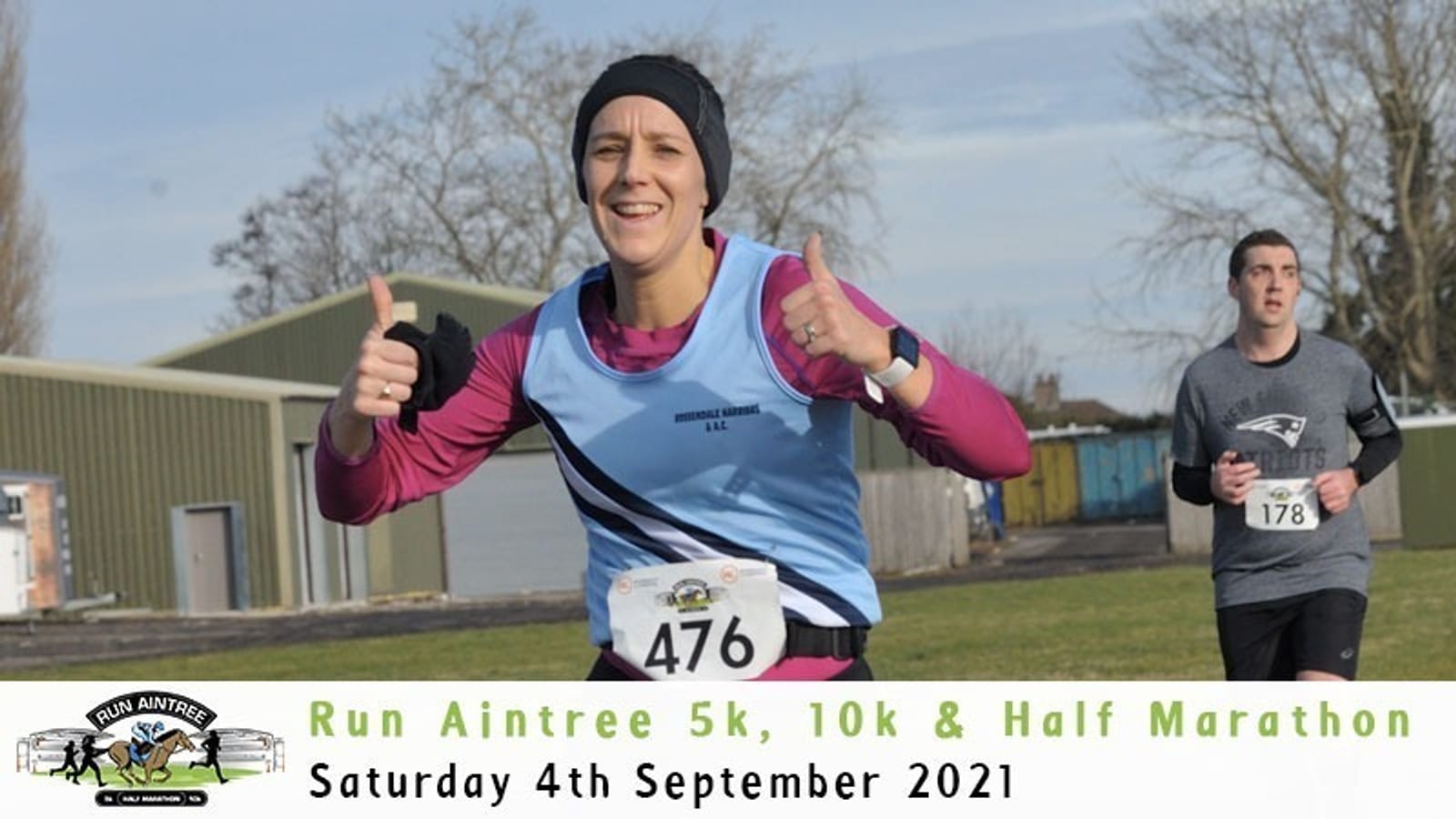 A person wearing a blue and pink sports outfit and race bib number 476 is running and giving a thumbs-up with both hands. Another runner is in the background. The text at the bottom reads "Run Aintree 5k, 10k & Half Marathon, Saturday 4th September 2021.