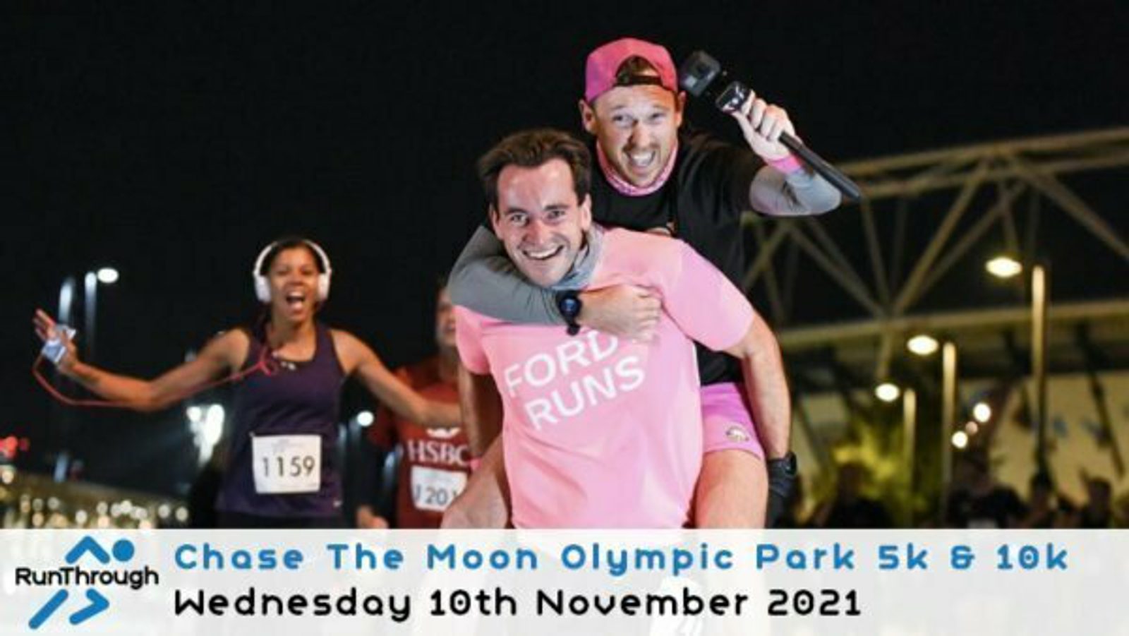 A man wearing a pink "FORD RUNS" shirt is giving a piggyback ride to a man in a black shirt and pink cap, smiling and holding a camera. A woman wearing a dark running outfit is running nearby. Text below reads "Chase The Moon Olympic Park 5k & 10k Wednesday 10th November 2021.