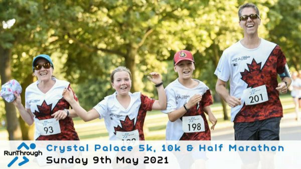 A smiling family of four, dressed in matching sports attire with maple leaf designs, runs together in a park. They hold hands as they participate in the Crystal Palace 5k, 10k, and Half Marathon event held on Sunday, May 9th, 2021.