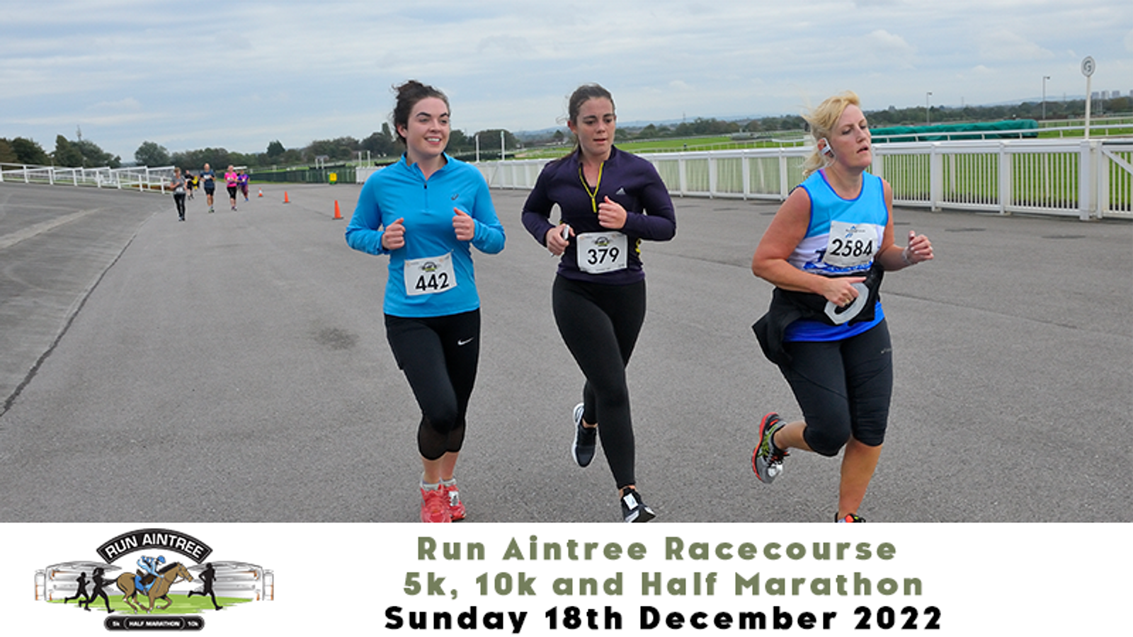 Three women are running on a racecourse during the Run Aintree Racecourse event on December 18, 2022. They are participating in a 5k, 10k, or half marathon race, wearing numbered bibs 442, 379, and 382. A logo of the event and race details are displayed at the bottom.