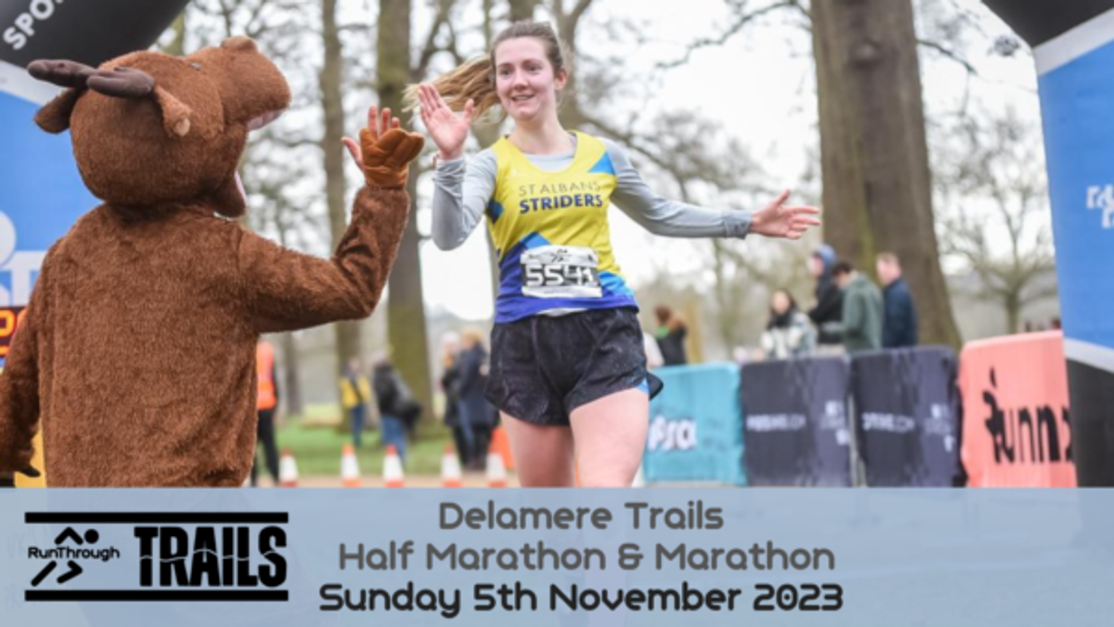 A female runner in "Stabba St Striders" gear high-fives a person in a deer costume while crossing the finish line at the Delamere Trails Half Marathon & Marathon on Sunday, 5th November 2023. A banner with event details is at the bottom of the image.