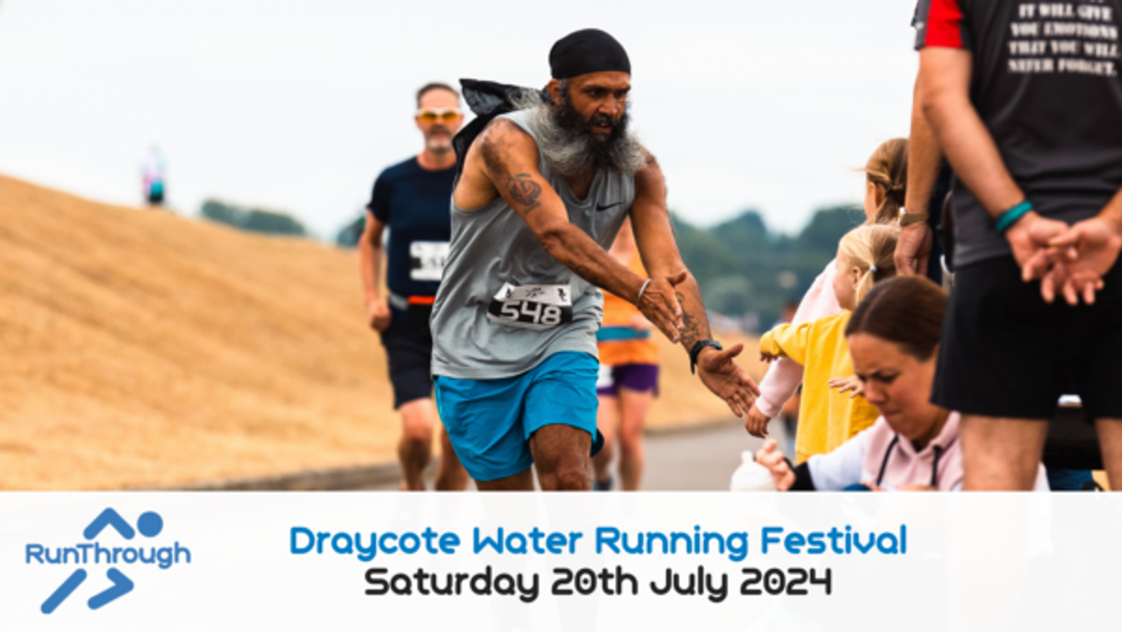 A runner wearing a gray shirt and blue shorts, sporting a beard and black headwear, high-fives supporters during the Draycote Water Running Festival. The race is scheduled for Saturday, July 20, 2024, as shown on the banner at the bottom of the image.