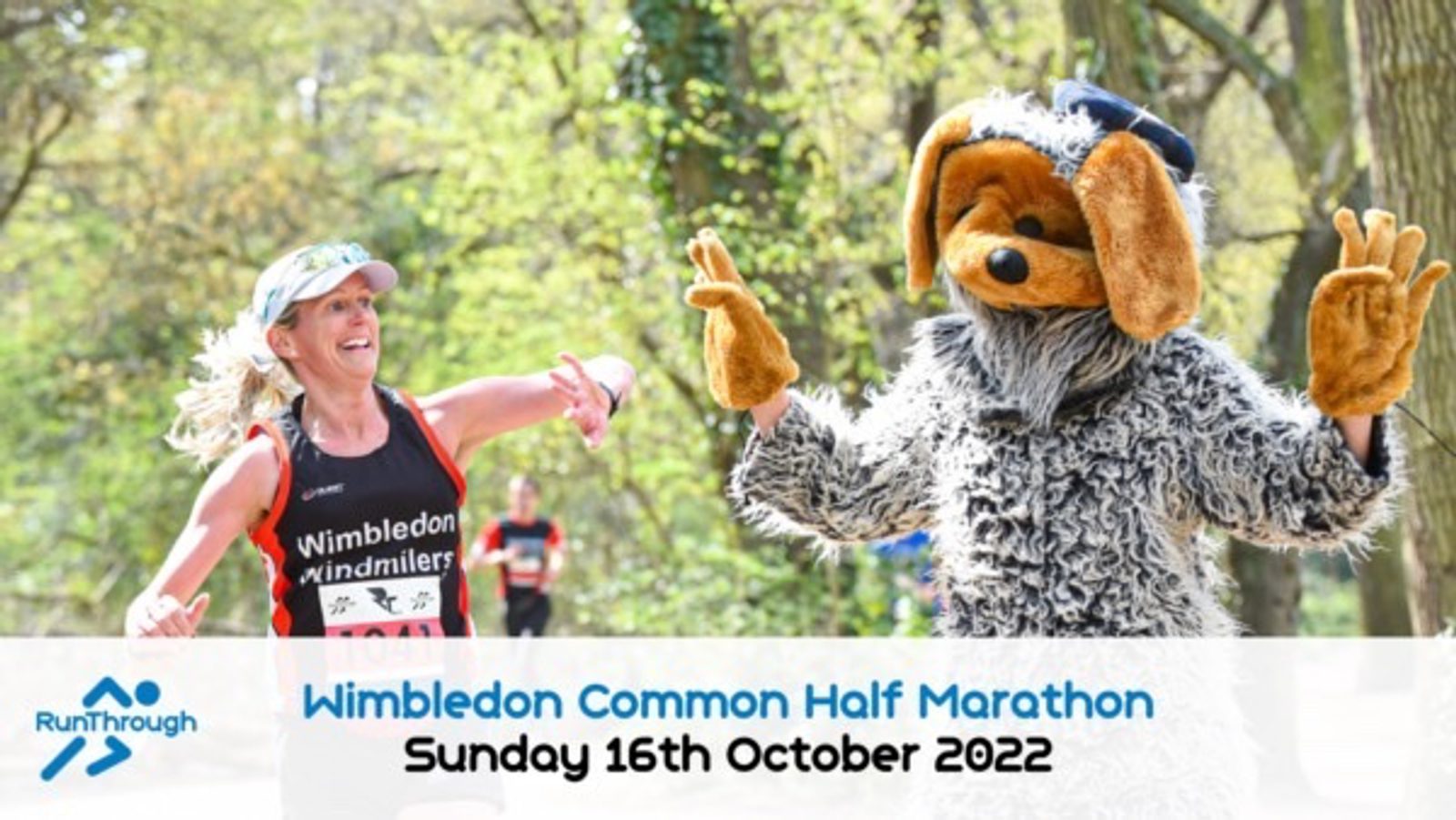 A runner in a Wimbledon Windmilers tank top is smiling and interacting with a person in a shaggy dog costume. Trees and other runners are in the background. Text at the bottom reads "Wimbledon Common Half Marathon Sunday 16th October 2022" next to the RunThrough logo.