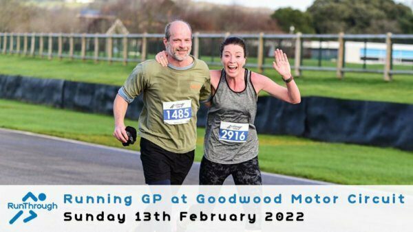Two runners are smiling and waving at the camera while participating in the Running GP at Goodwood Motor Circuit on Sunday, 13th February 2022. The male runner wears a green shirt with the number 1485, and the female runner wears a gray shirt with the number 2916.
