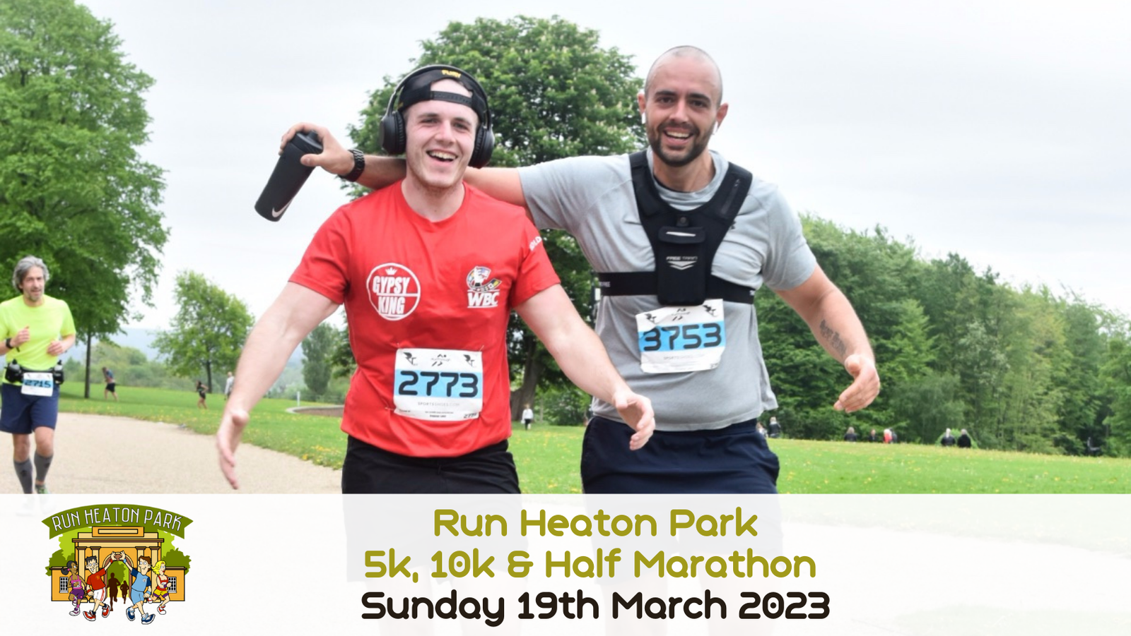 Two runners are smiling and giving thumbs-up as they participate in the "Run Heaton Park" event on March 19th, 2023. Both are wearing running attire with race bibs, one in a red shirt and the other in a grey shirt. There are trees and other runners in the background.