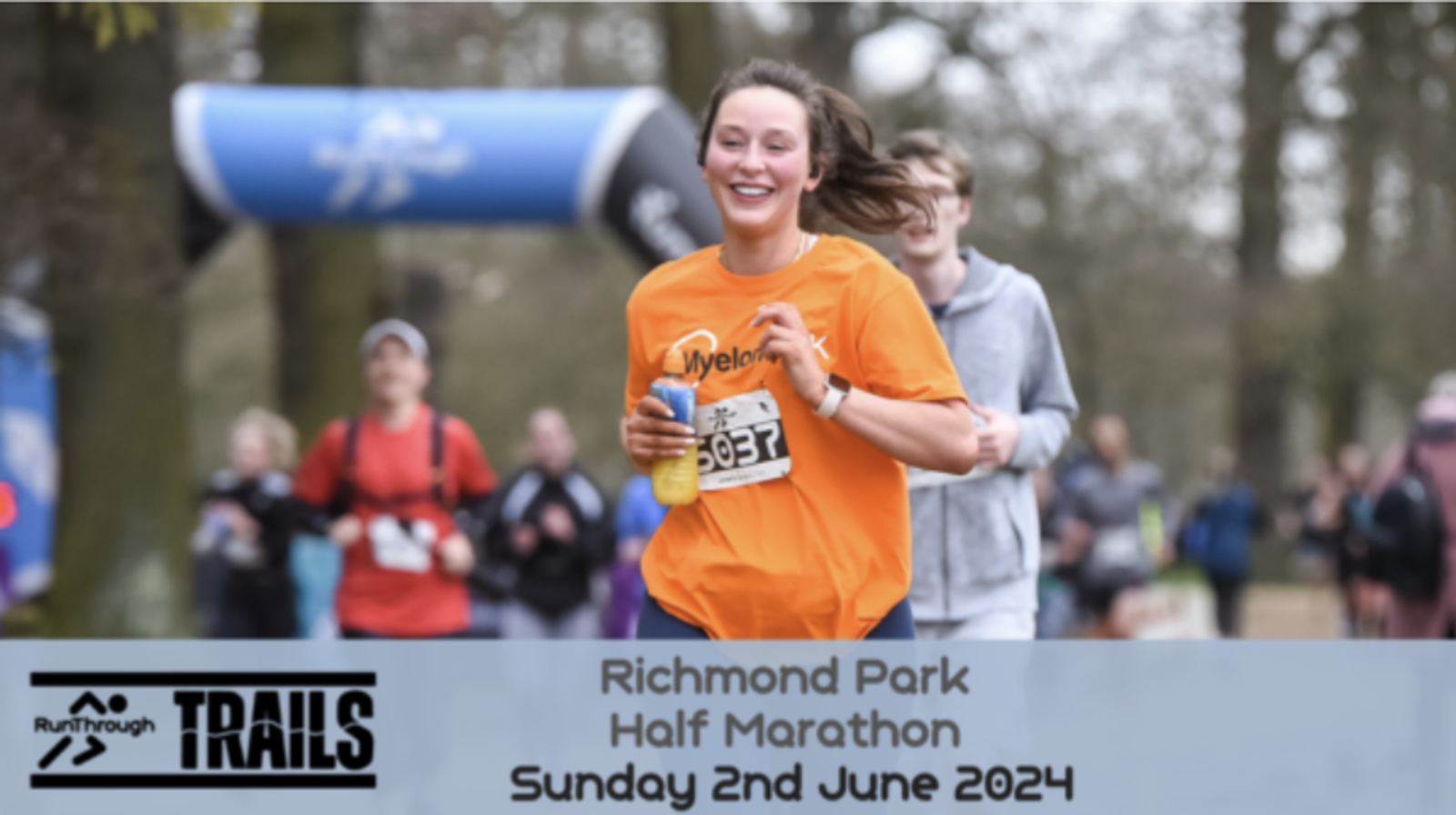 A woman in an orange shirt is running towards the camera, smiling, during the Richmond Park Half Marathon with other runners in the background. The event details, "Richmond Park Half Marathon Sunday 2nd June 2024," are displayed at the bottom of the image.