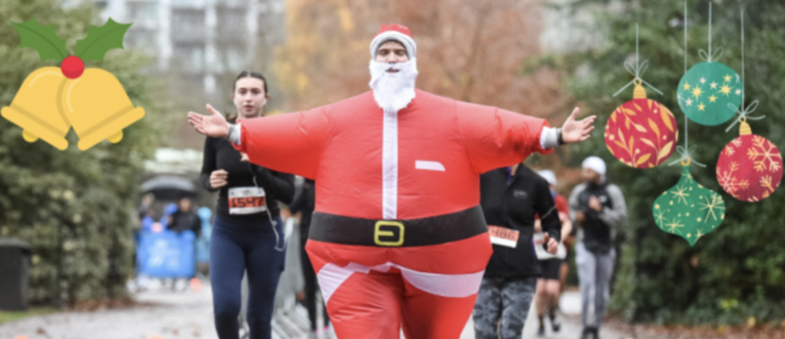 A person dressed in an inflatable Santa Claus costume is joyfully running in a race surrounded by other runners. Decorative Christmas elements like bells and ornaments are overlaid on the image, enhancing the festive atmosphere.