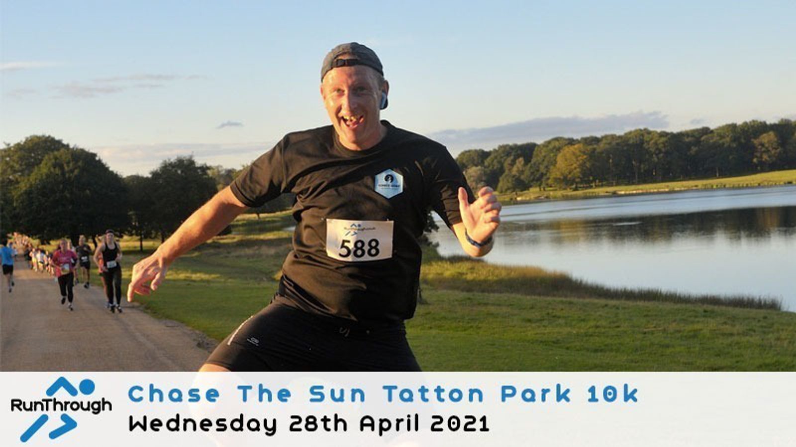 A man wearing a black outfit and race number 588 is running with a smile, making a thumbs-up gesture. The scene is outdoors on a sunlit path near a lake, with other runners visible in the background. The text reads: "Chase The Sun Tatton Park 10k, Wednesday 28th April 2021.