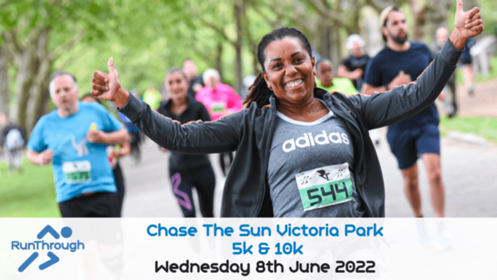 Joyful runner in a black jacket and grey Adidas shirt gives a thumbs up while participating in the "Chase The Sun Victoria Park 5k & 10k" event on Wednesday, 8th June 2022. Other runners are seen in the background. The event logo is displayed on the bottom left.