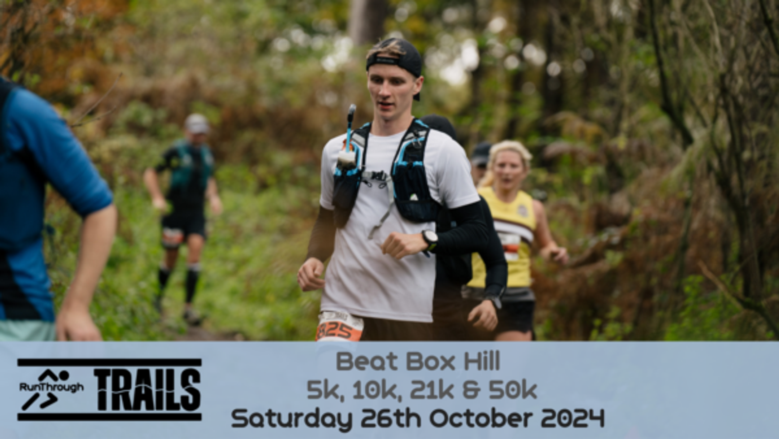 A group of runners navigate a forest trail during the "Beat Box Hill" event. The event details, including "5k, 10k, 21k & 50k, Saturday 26th October 2024," are prominently displayed at the bottom with the RunThrough TRAILS logo.