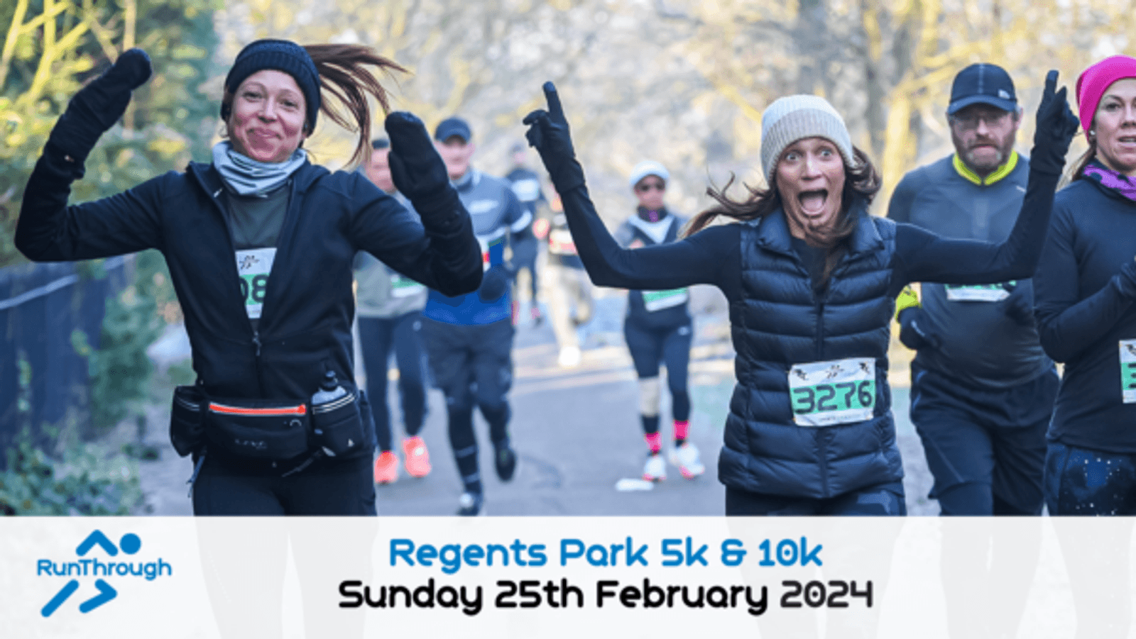 Two women, dressed in winter running gear and wearing race numbers, joyfully run with outstretched arms during a race. Other runners can be seen behind them. Text at the bottom reads, "Regents Park 5k & 10k Sunday 25th February 2024" next to the RunThrough logo.