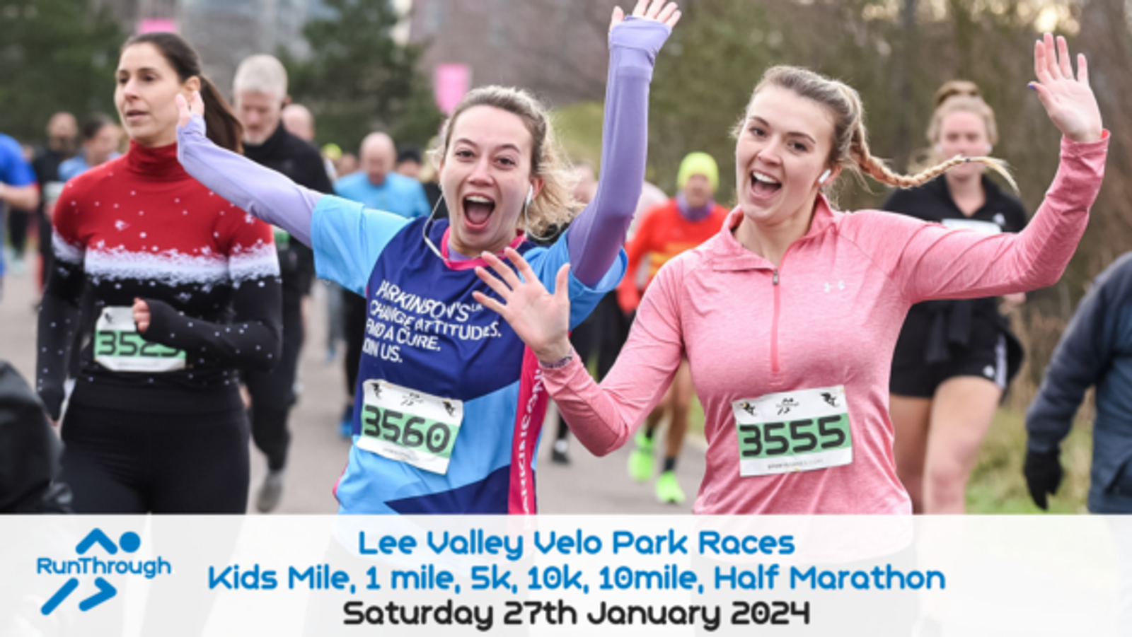 Two smiling runners, wearing numbered bibs 3550 and 3555, wave at the camera during the Lee Valley Velo Park Races. The event, scheduled for Saturday 27th January 2024, includes various race distances: Kids Mile, 1 mile, 5k, 10k, 10 mile, and a Half Marathon.