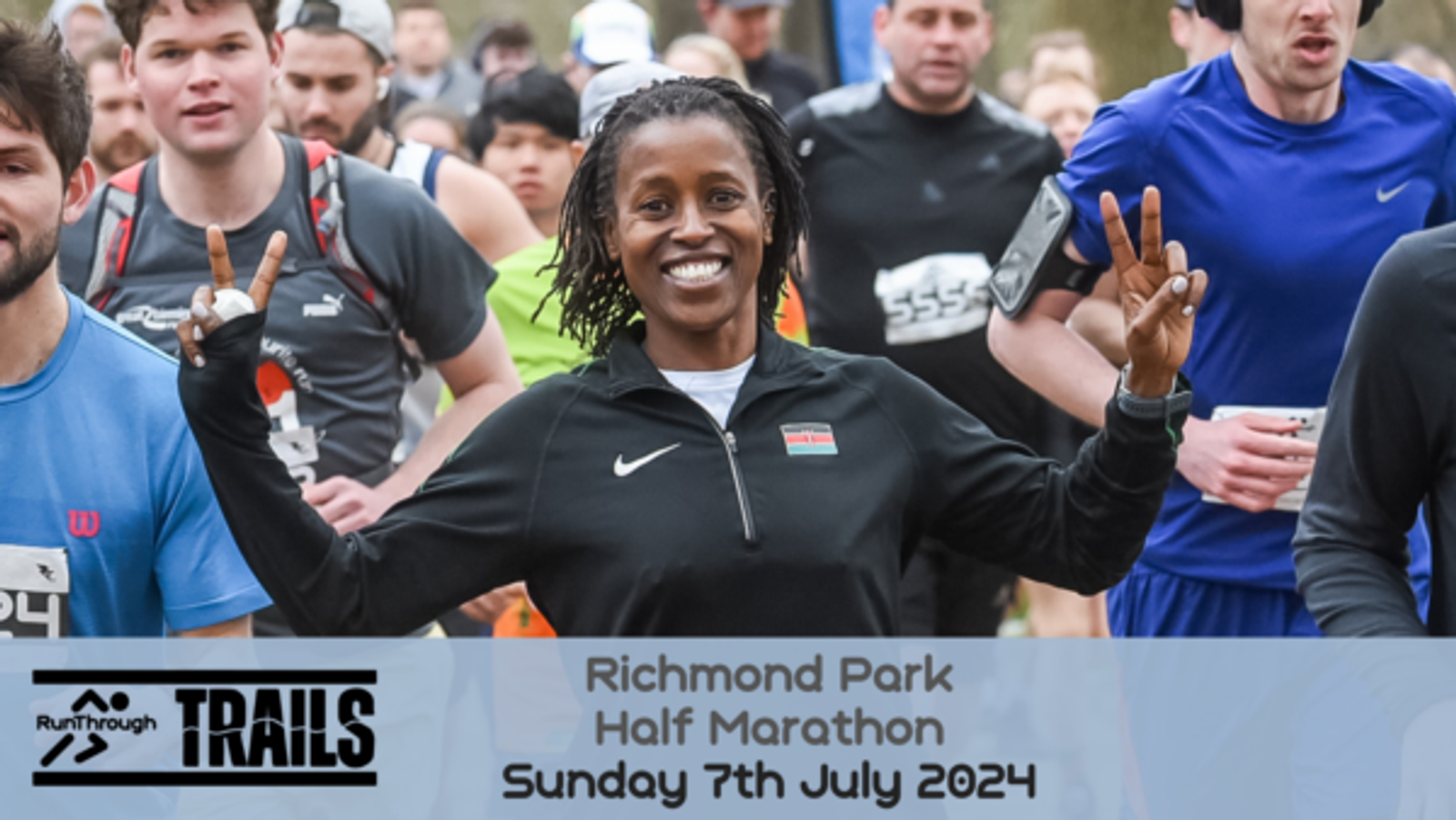 A smiling woman in a black athletic jacket flashes a peace sign with both hands while running among a group of participants in a marathon. A banner at the bottom reads "Richmond Park Half Marathon Sunday 7th July 2024" with the "RunThrough Trails" logo on the left.