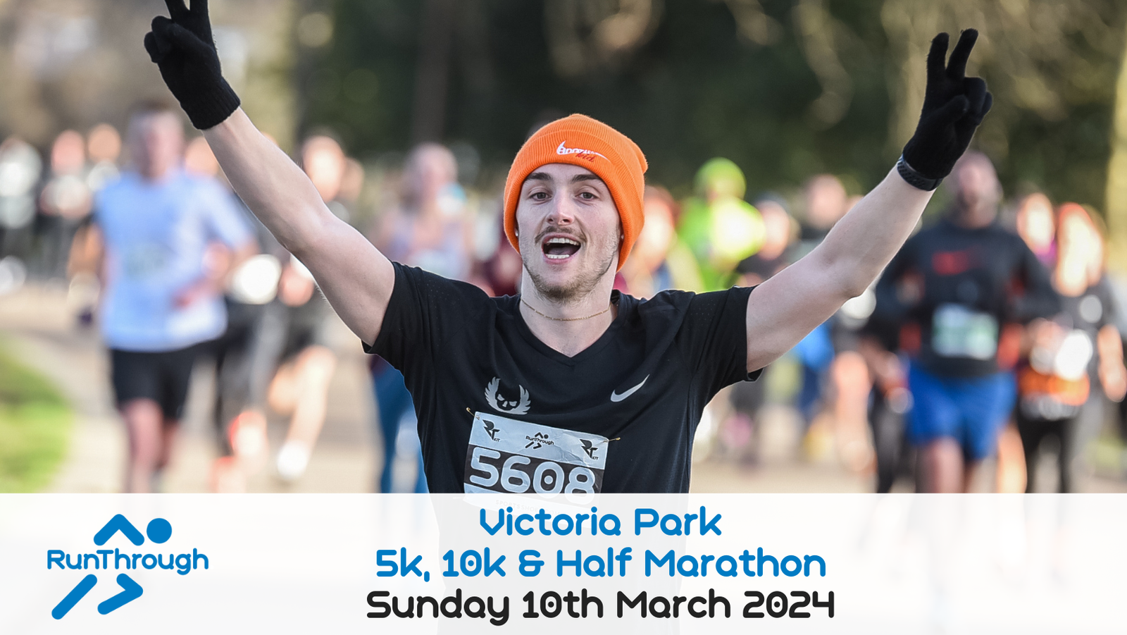 A man wearing a black shirt and orange beanie raises his arms in celebration as he runs. Many other runners are behind him. The text at the bottom reads: "RunThrough Victoria Park 5k, 10k & Half Marathon Sunday 10th March 2024.