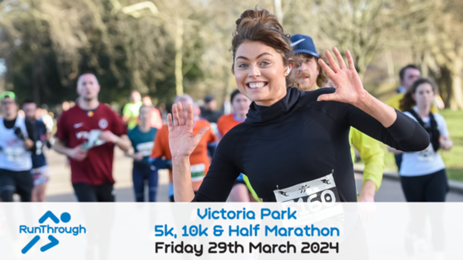 A group of runners racing in Victoria Park. A smiling woman in a black long-sleeve shirt is prominently in the foreground, waving her hands. Text at the bottom reads "Victoria Park 5k, 10k & Half Marathon, Friday 29th March 2024" and includes the RunThrough logo.