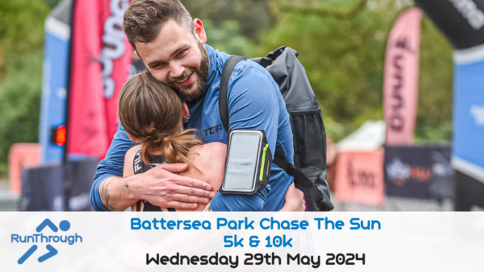 Two runners embrace joyfully at the finish line of the Battersea Park Chase The Sun 5k & 10k event. The man has a fitness tracker on his arm, and banners are visible in the background. Text at the bottom reads, “Battersea Park Chase The Sun 5k & 10k, Wednesday 29th May 2024.”.