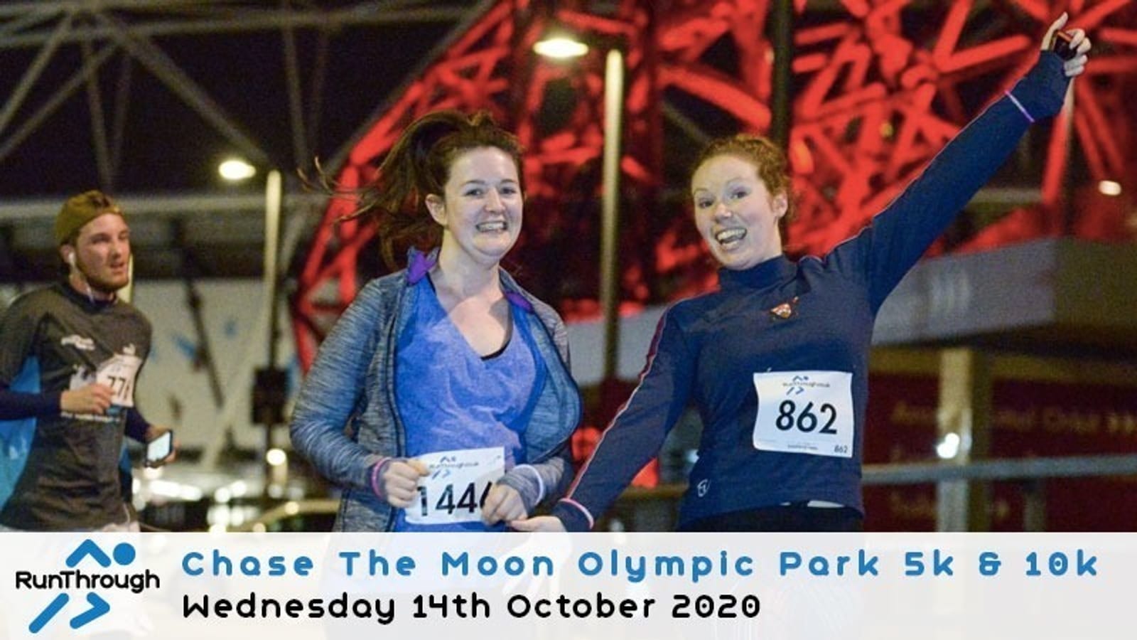 Two women running together, both smiling, during a night race event against a backdrop of red-lit structures. They wear race numbers 144 and 862. Other runners and event banners are in the background. Text at the bottom reads, "Chase The Moon Olympic Park 5k & 10k, Wednesday 14th October 2020.