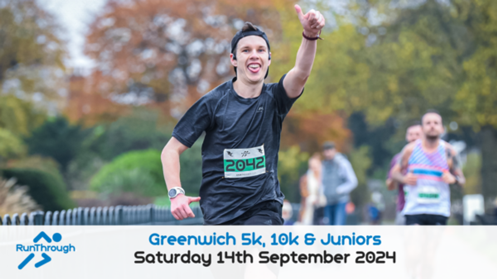 A runner wearing a black cap and shirt with the number 2042 pinned to his chest smiles and points a finger in the air during a race. The text "Greenwich 5k, 10k & Juniors, Saturday 14th September 2024" is at the bottom of the image with a logo on the left.