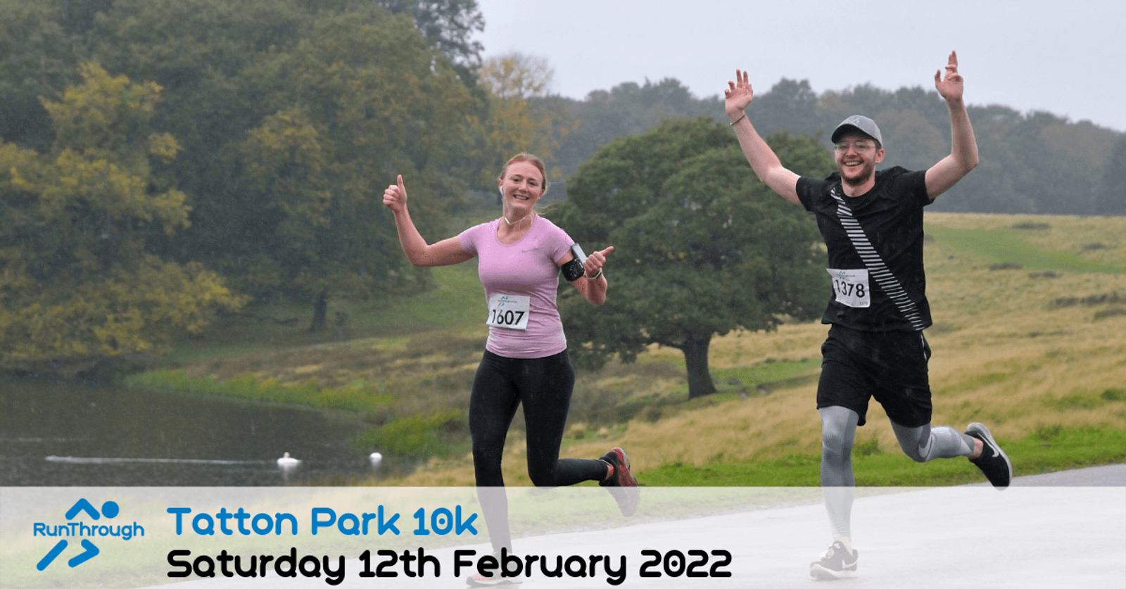 Two smiling runners, a woman and a man, raise their arms in celebration as they run outdoors by a lake and trees. The image promotes the Tatton Park 10k event on Saturday, 12th February 2022.
