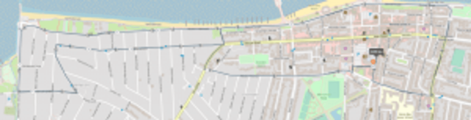Map showing streets in a coastal city. The coast is at the top, with detailed street layouts, buildings, parks, and waterways below. A highlighted route begins near the coast and extends to the center of the map.
