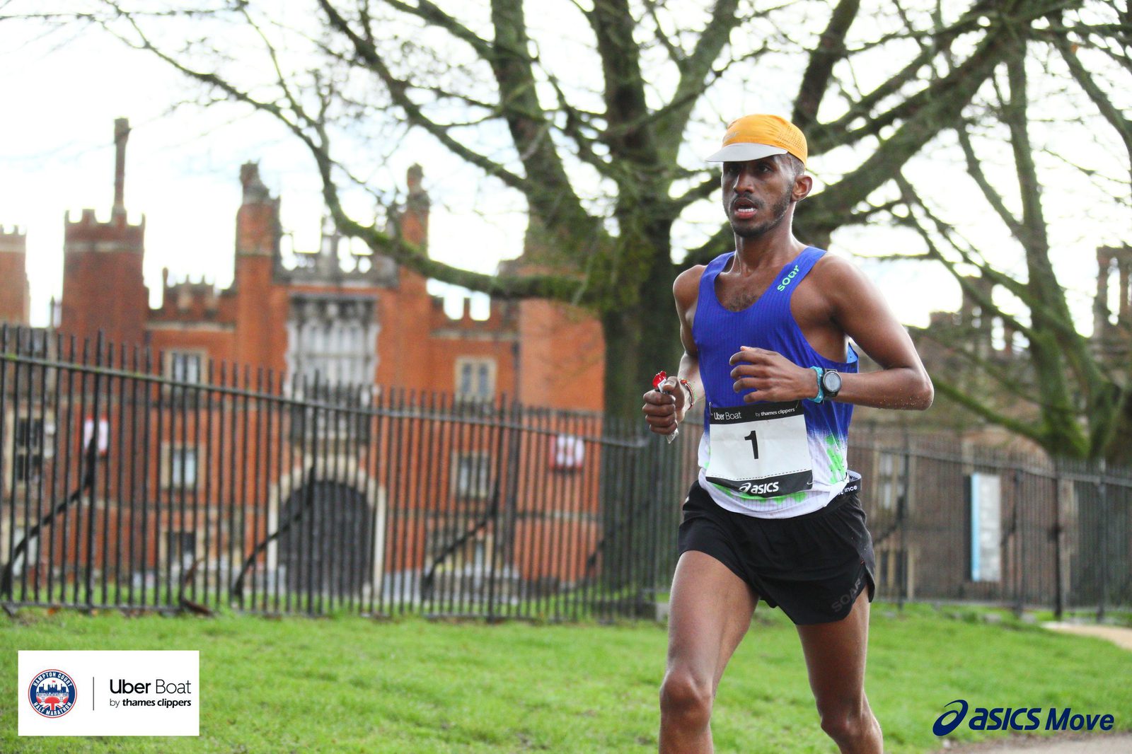 A runner wearing a blue tank top, black shorts, and a yellow cap is participating in a race. He is running near a historic brick building with trees in the background. The race is sponsored by Uber Boat and ASICS Move, as indicated by logos and text on the image.