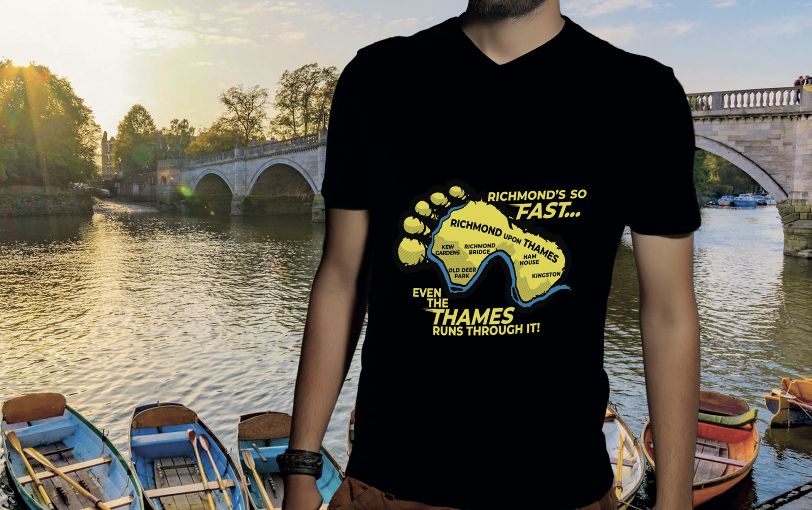 A person stands in front of a river dotted with rowboats and a bridge at sunset. They are wearing a black T-shirt with a colorful map and text that reads, "Richmond's so fast... Even the Thames runs through it!.