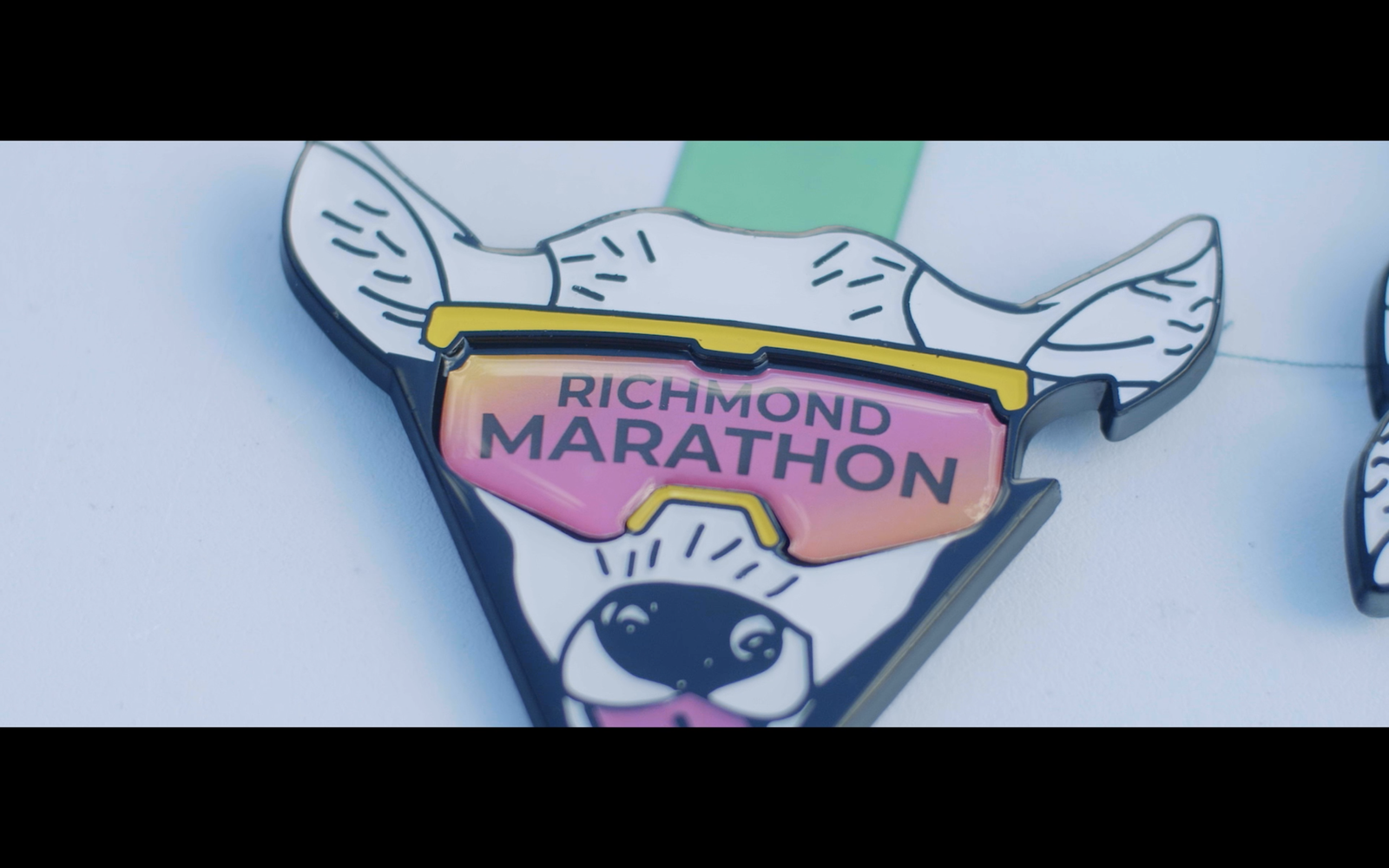 A medal featuring an illustration of a dog wearing large sunglasses. The sunglasses have reflective lenses displaying the text "RICHMOND MARATHON." The dog's ears are perked up, and it has a whimsical, cartoonish appearance.