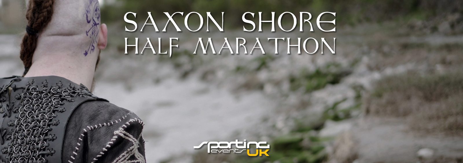 A person with a unique hairstyle and intricate clothing stands facing away from the camera, looking towards a rocky coastline. The text above reads "Saxon Shore Half Marathon." The bottom of the image features the logo for specture events UK.