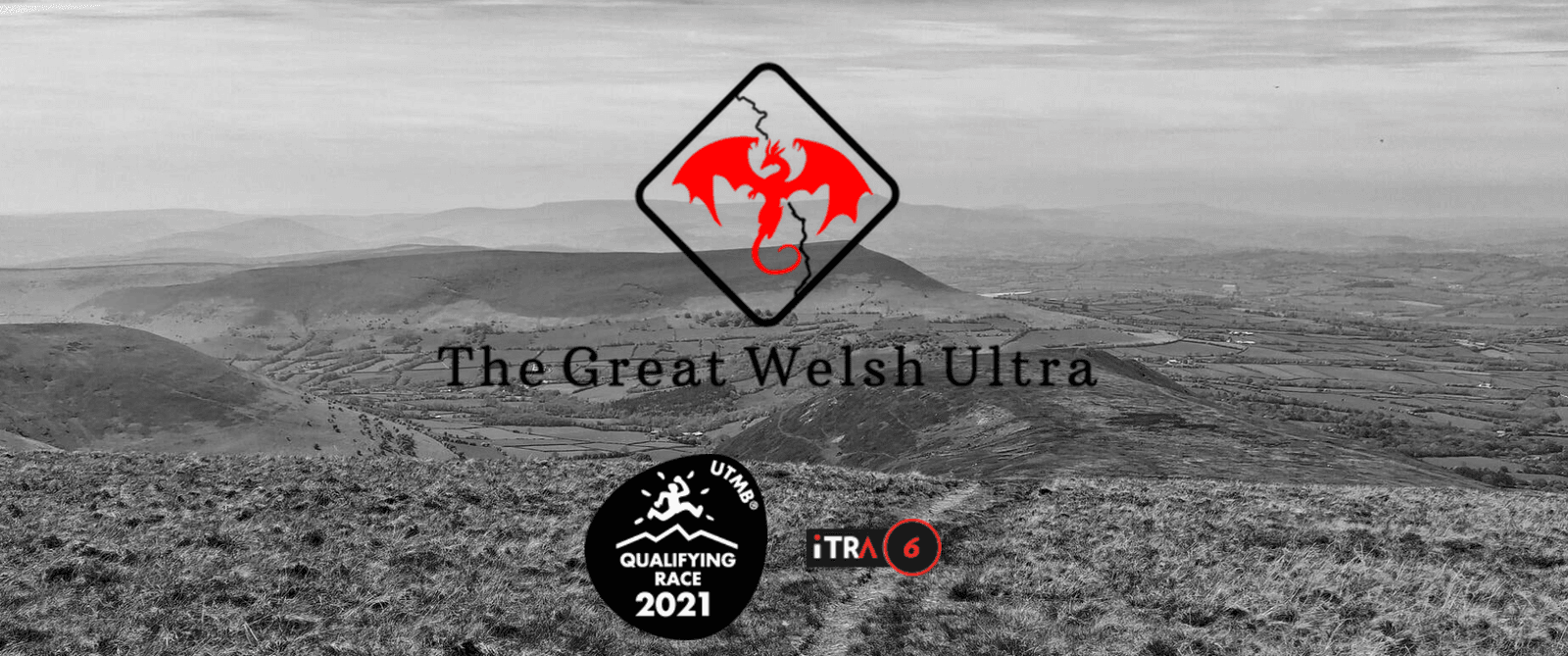 A black-and-white landscape photo shows rolling hills under a cloudy sky. The Great Welsh Ultra logo, featuring a red dragon inside a diamond shape, is centered. Two additional logos at the bottom represent a 2021 qualifying race and an iTRA rating of 6.