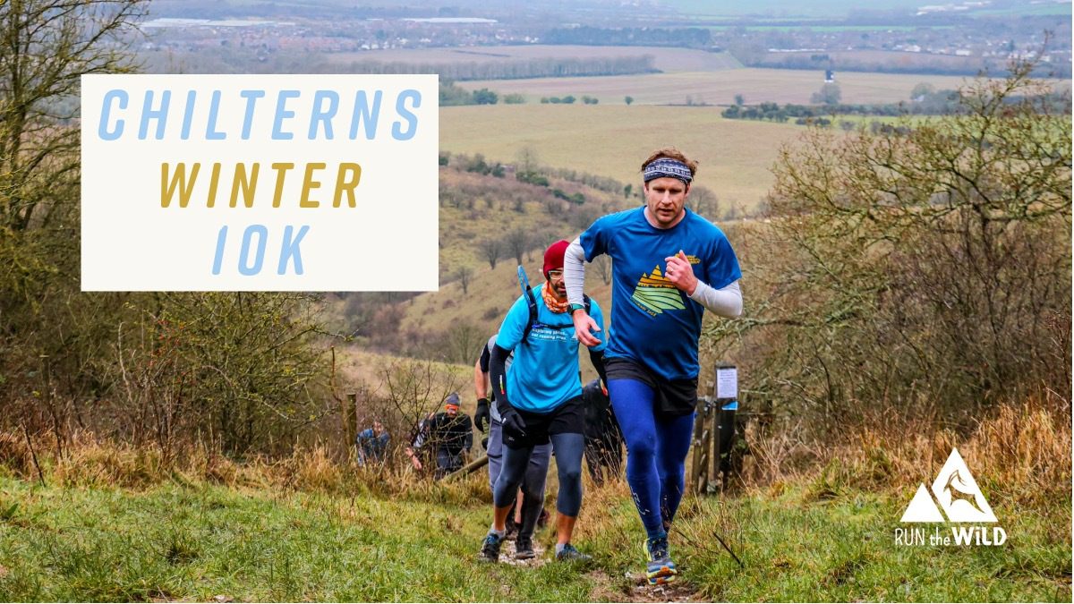 Runners in blue shirts climb a grassy hill during a race, with scenic countryside in the background. Text reads "Chilterns Winter 10K." The "Run the Wild" logo is in the corner.