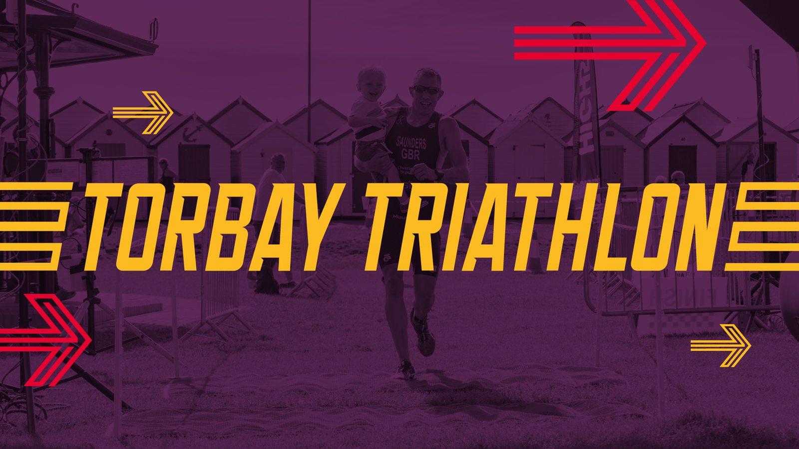 A person carrying a child crosses the finish line at the Torbay Triathlon event. The bold yellow text "Torbay Triathlon" is overlaid on the image, with red and yellow arrows pointing towards the text from various directions.
